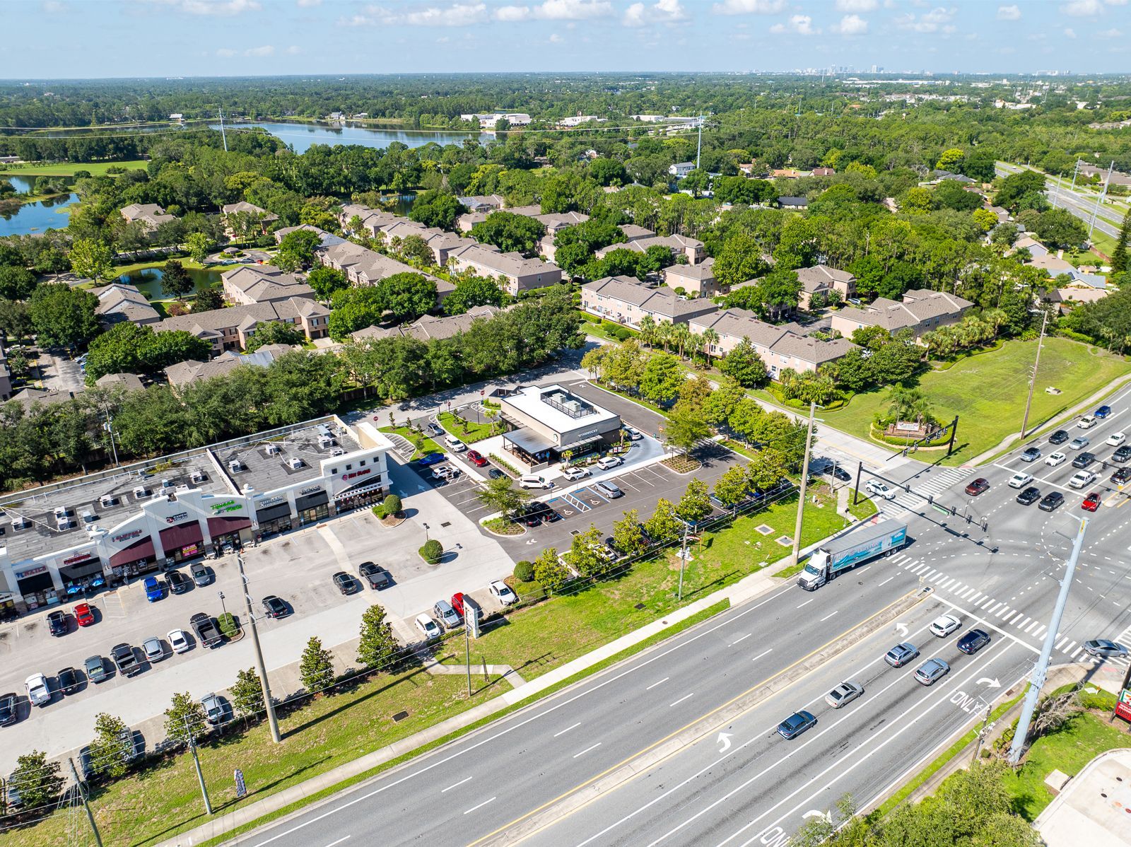 An aerial view of a residential area with a parking lot and a highway.