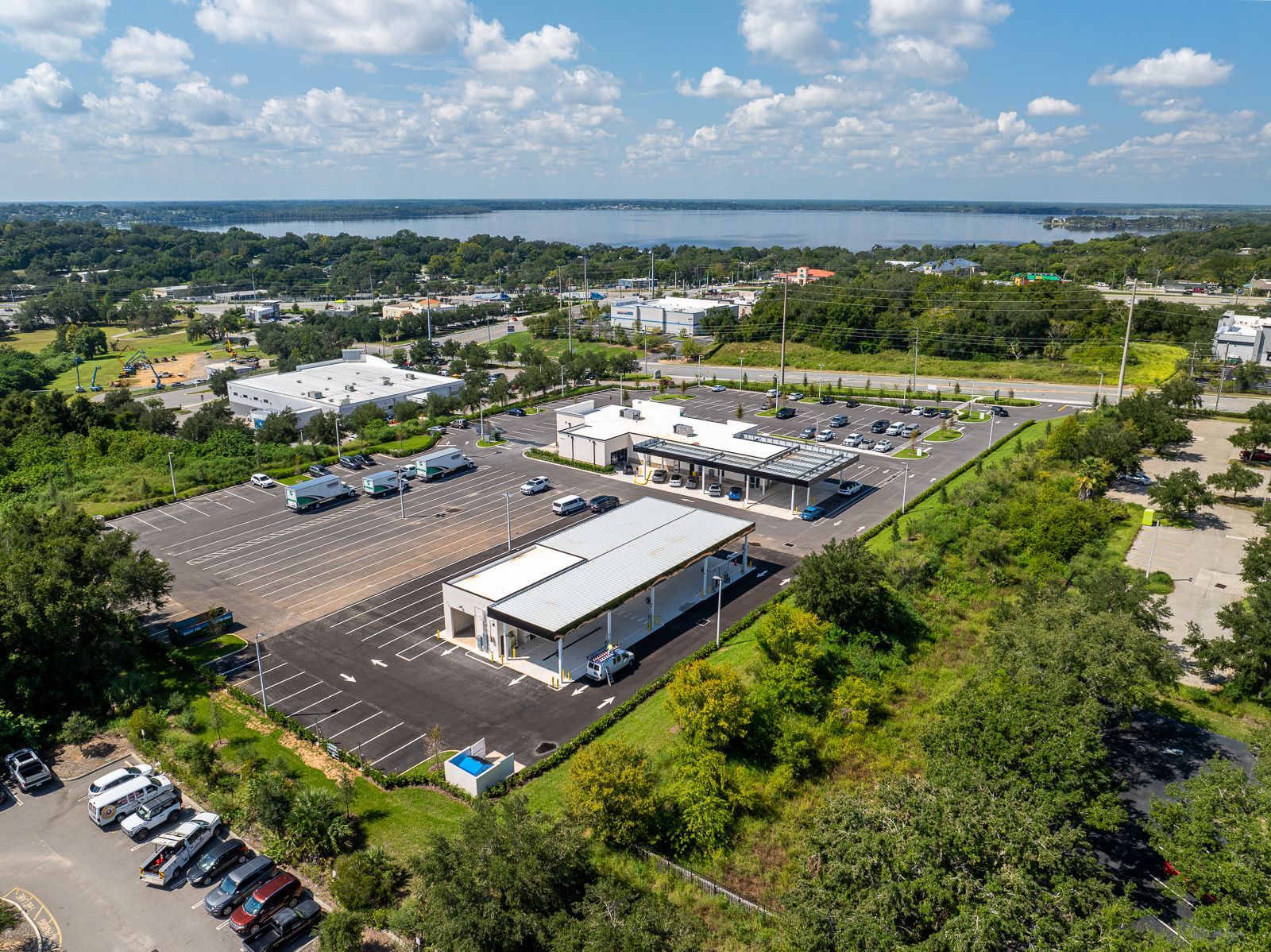An aerial view of a parking lot with a building in the background and a lake in the background.