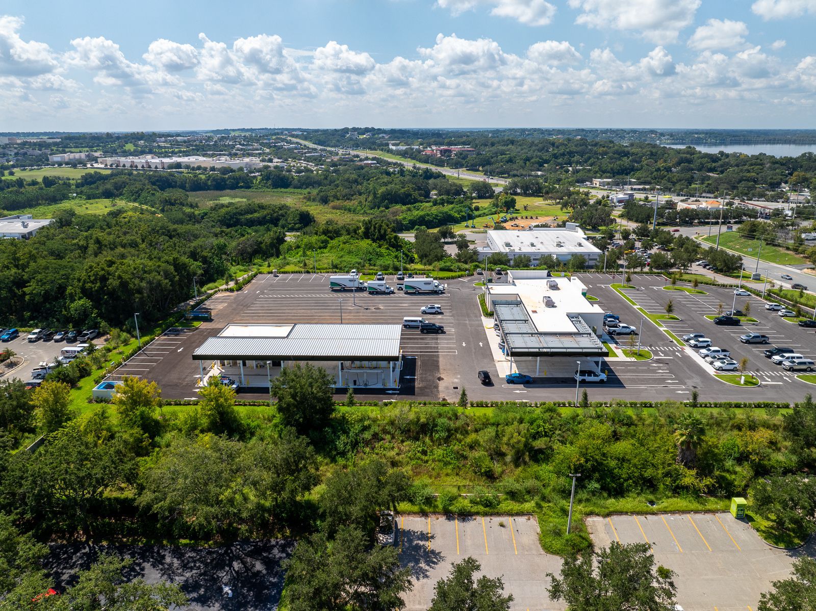 An aerial view of a large parking lot surrounded by trees and buildings.