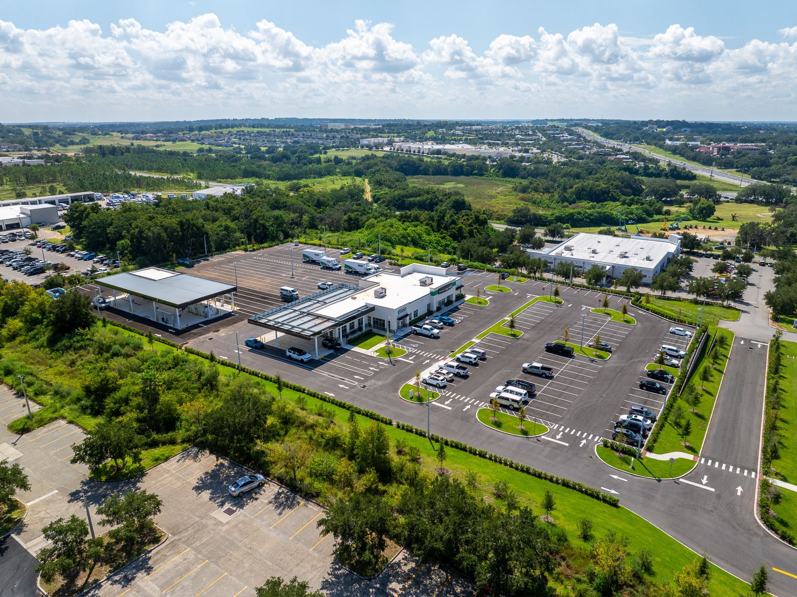 An aerial view of a large parking lot surrounded by trees and buildings.