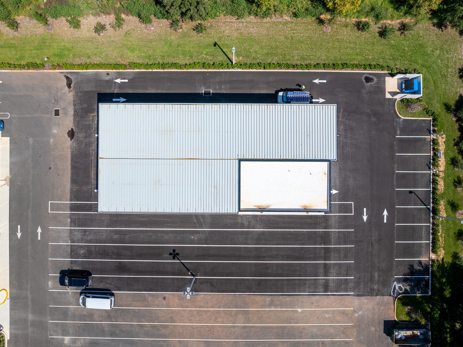 An aerial view of a parking lot with a building in the background.