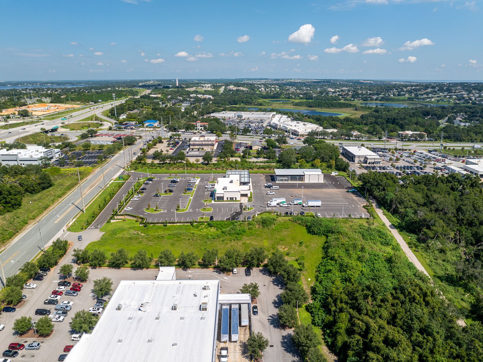An aerial view of a large white building surrounded by trees and a parking lot.