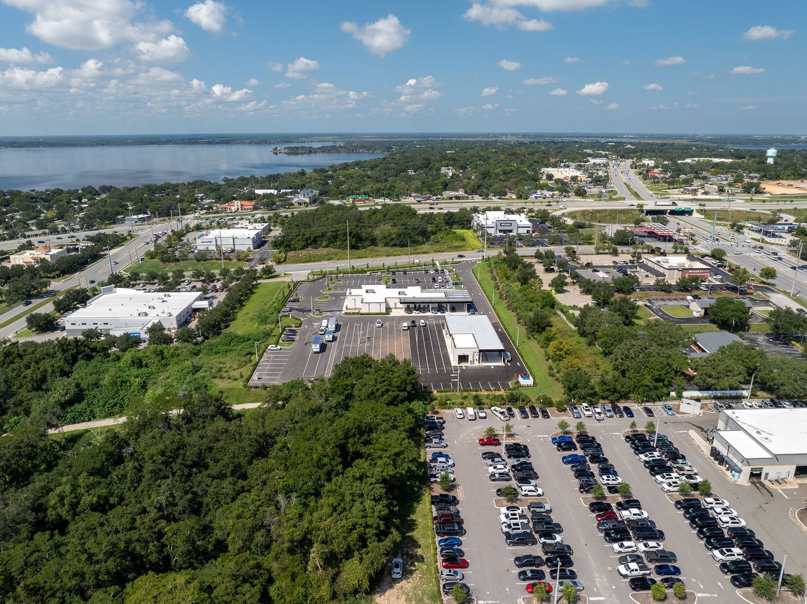 An aerial view of a parking lot in a city with a lake in the background.