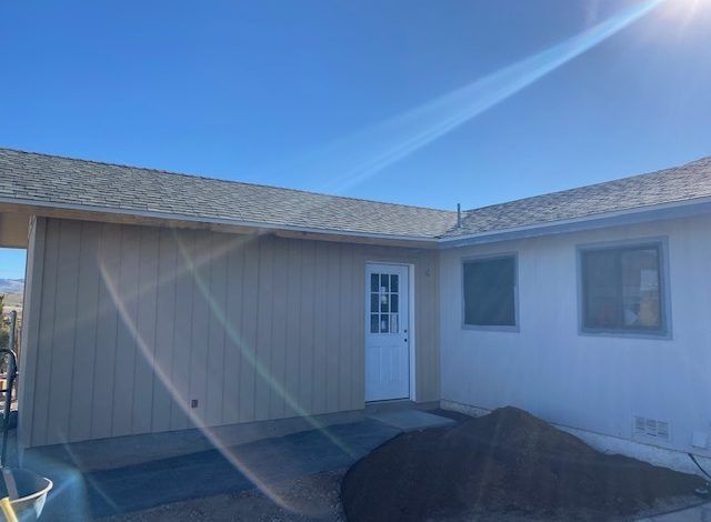 Single-story beige house exterior with a white door and bright blue sky glare