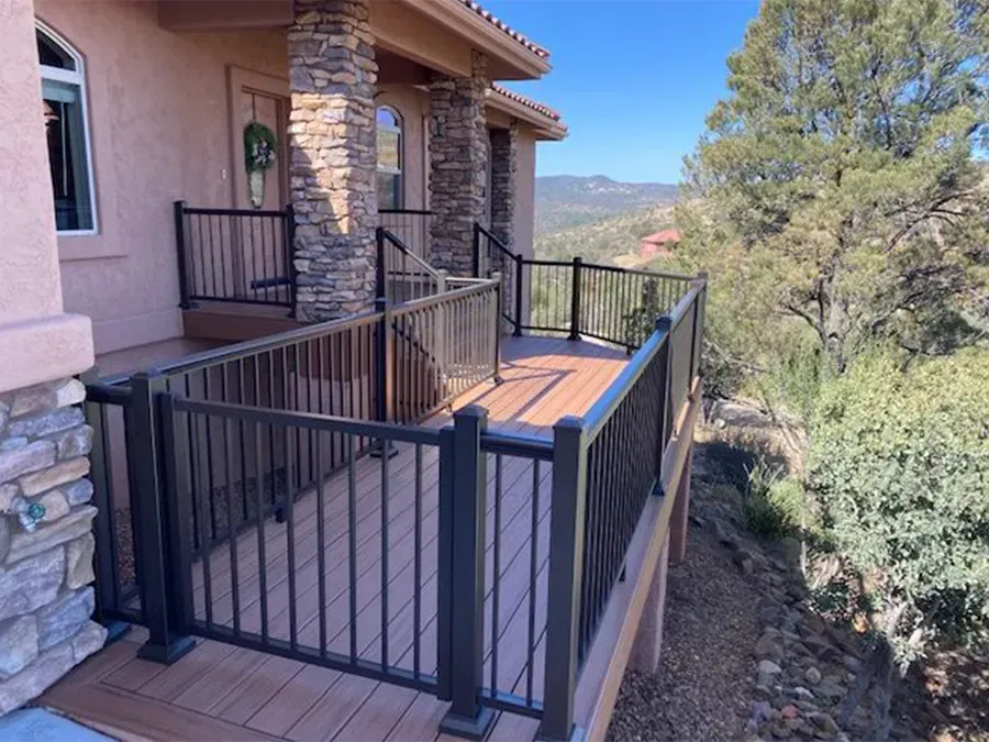 Stone house balcony with black railing and wood deck overlooking a hillside view