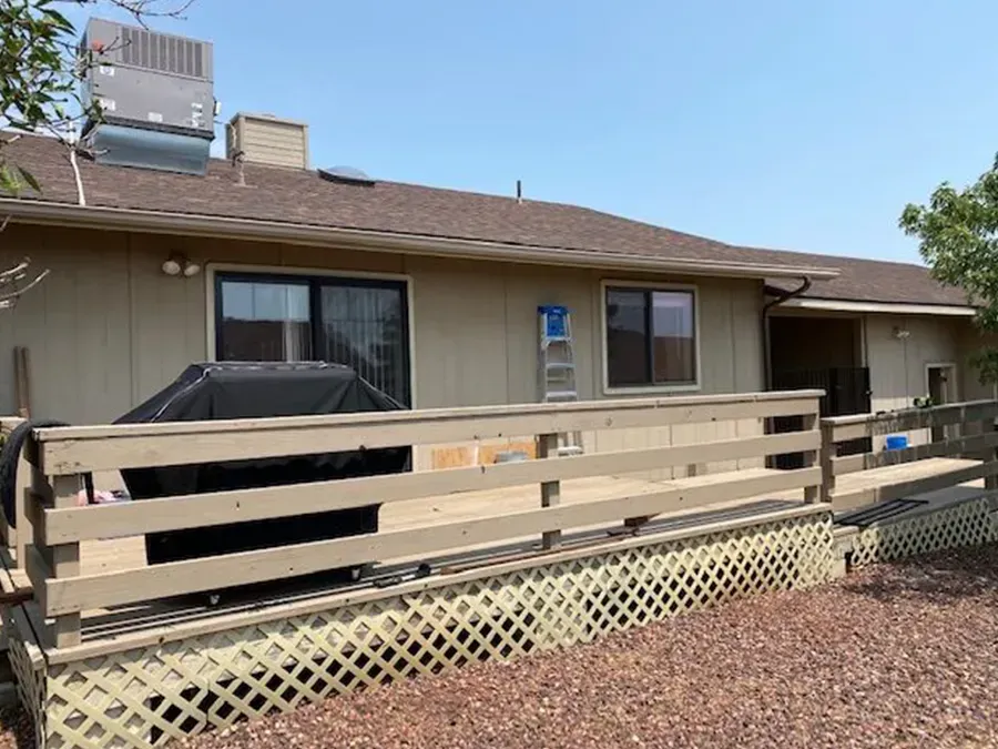 Single-story beige house with a wooden ramp and railing in the front yard