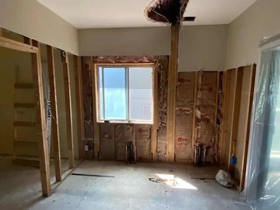 Renovated room with exposed framing, unfinished walls, and a window letting in sunlight