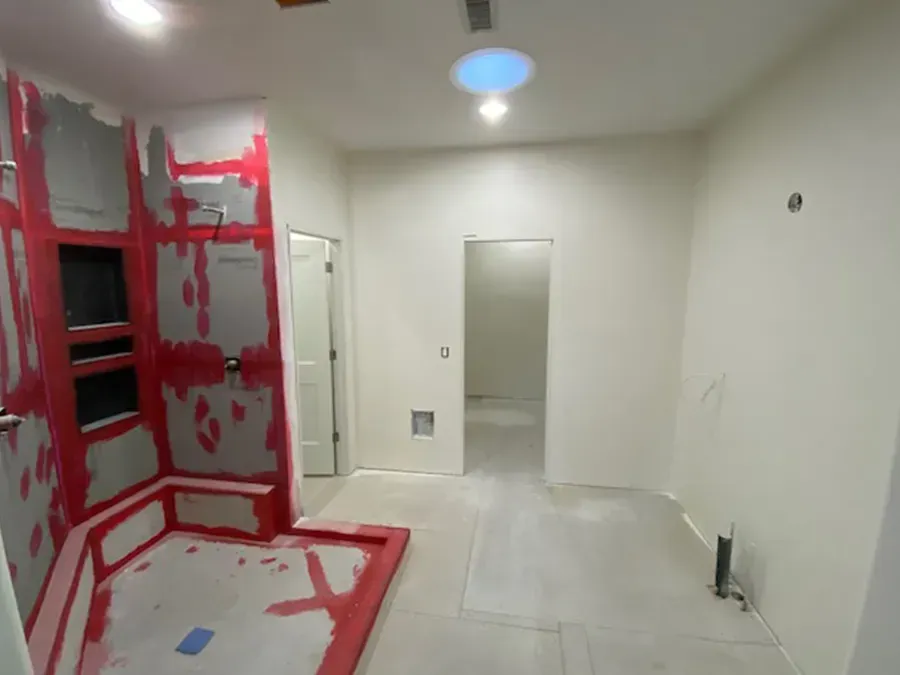 Small unfinished room with white walls, red-painted trim, and a tiled floor under construction.