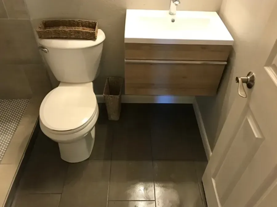 Small bathroom with toilet, sink vanity, and dark tiled floor