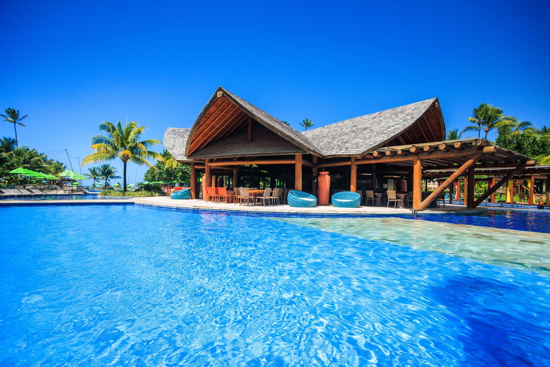 Uma grande piscina com um prédio de madeira ao fundo.