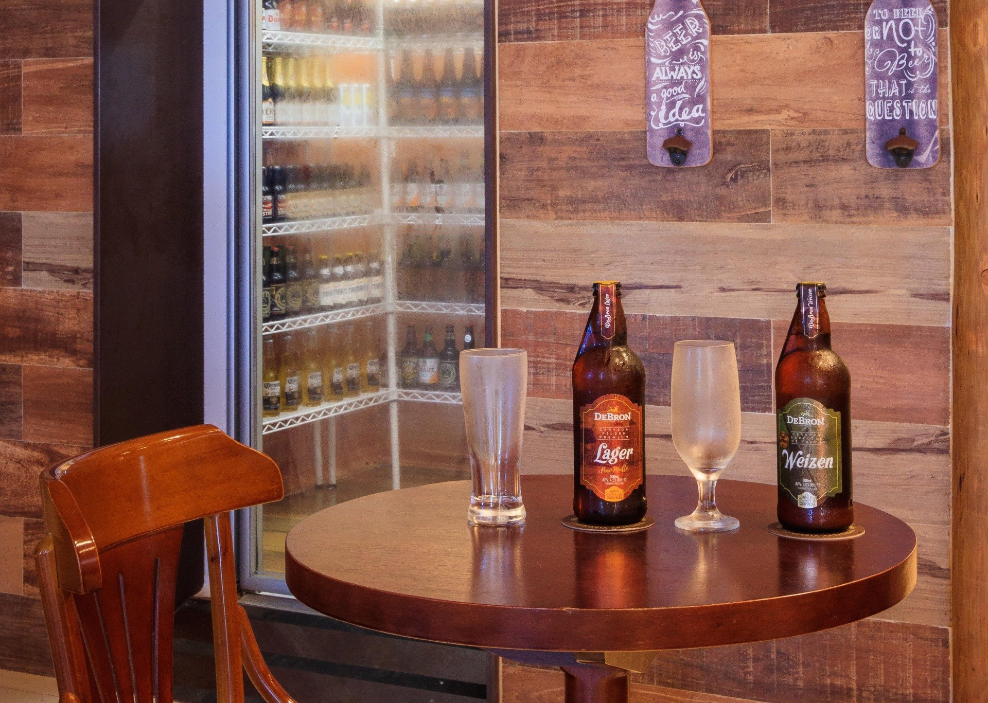 Uma mesa com três garrafas de cerveja e dois copos sobre ela.
