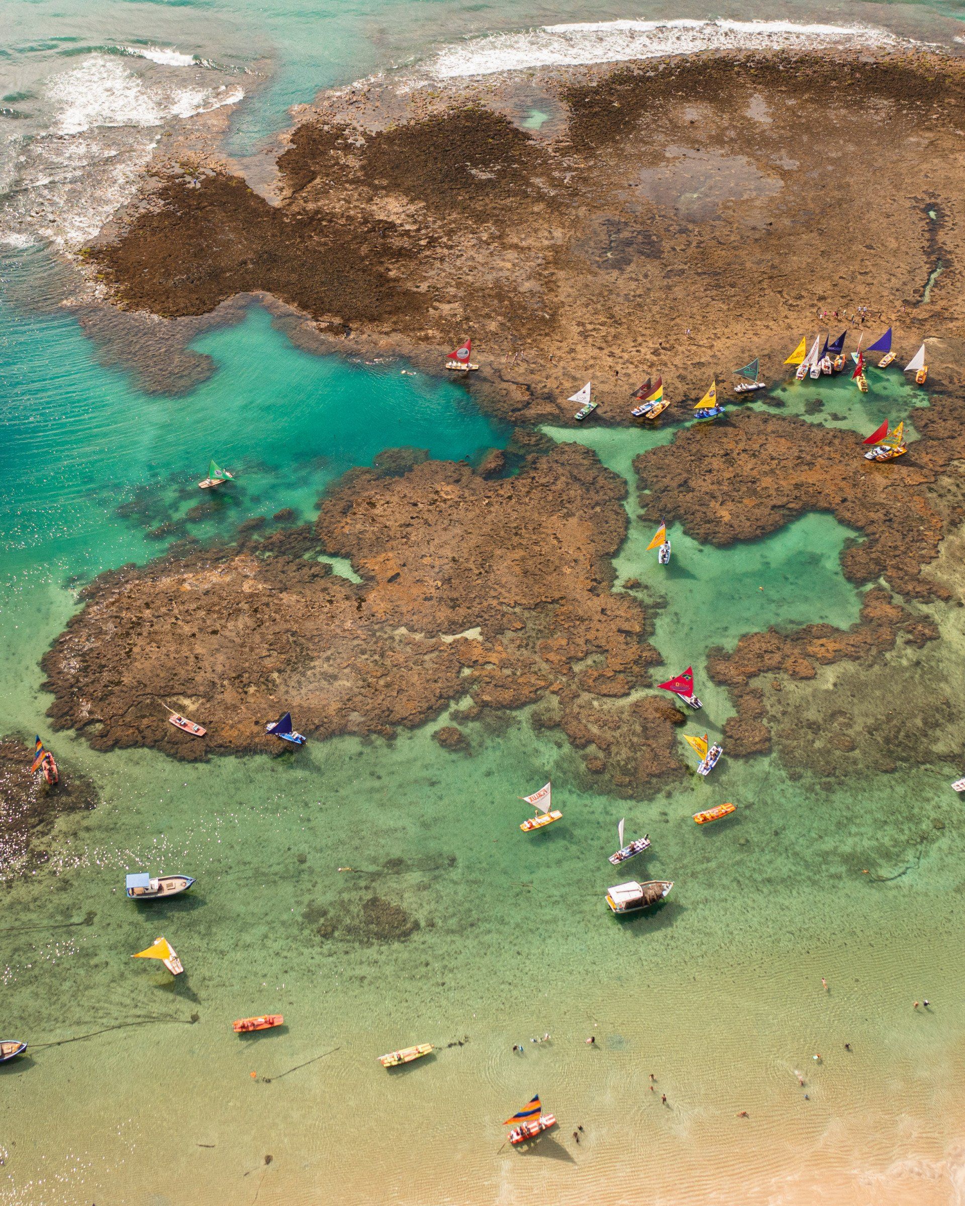 Uma vista aérea de uma praia com barcos e pessoas na água.