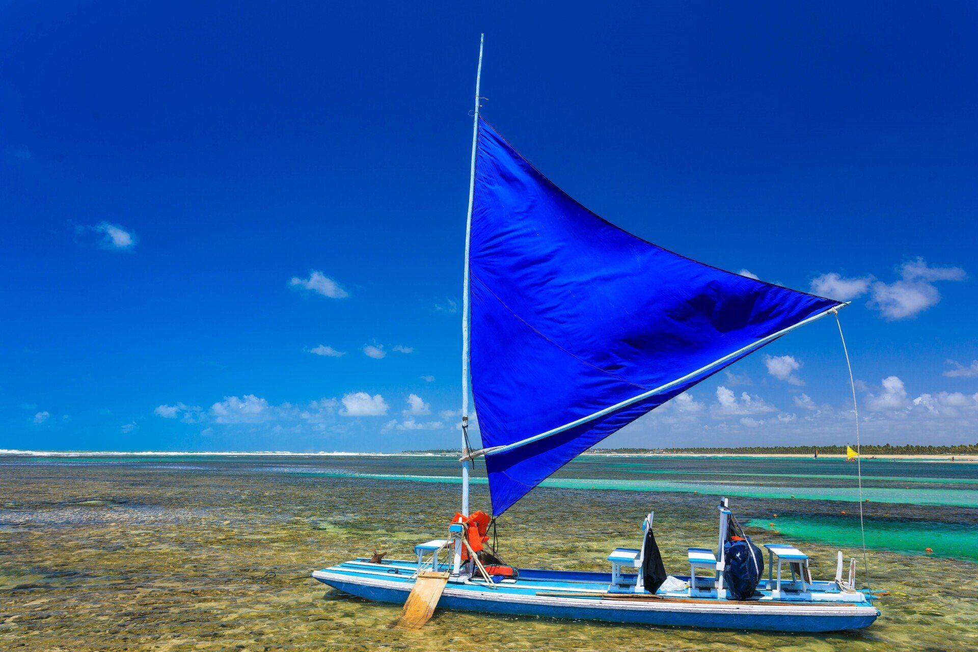 Um barco com uma vela azul está flutuando sobre um corpo d'água.