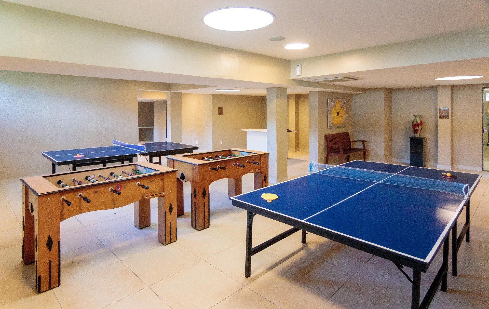 Uma sala de jogos com mesas de pingue-pongue e pebolim