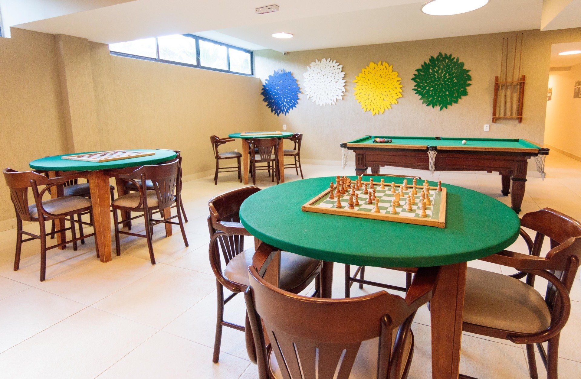 Uma sala com mesas e cadeiras e uma mesa de sinuca com um tabuleiro de xadrez.