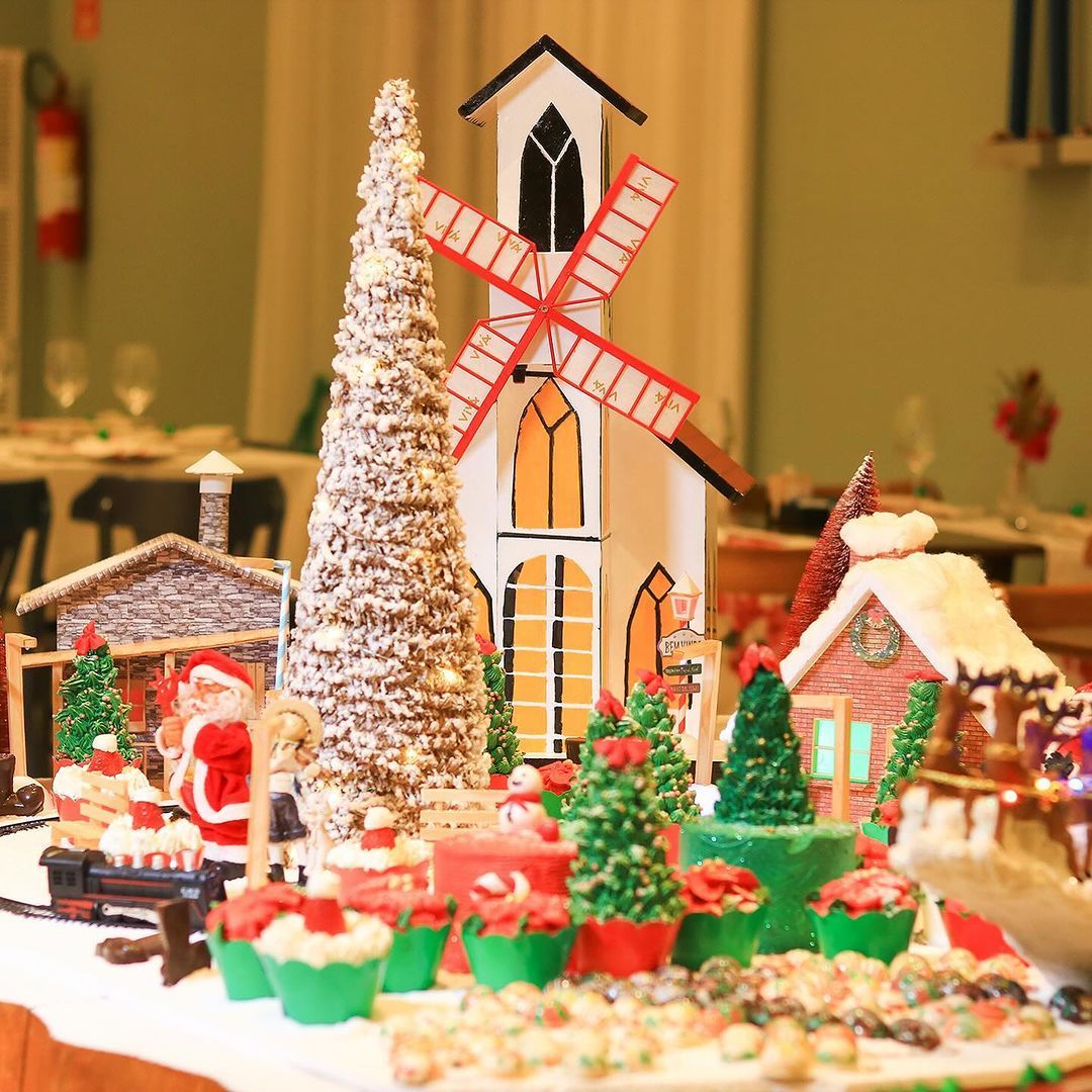 Uma mesa cheia de decorações de Natal, incluindo Papai Noel e um moinho de vento