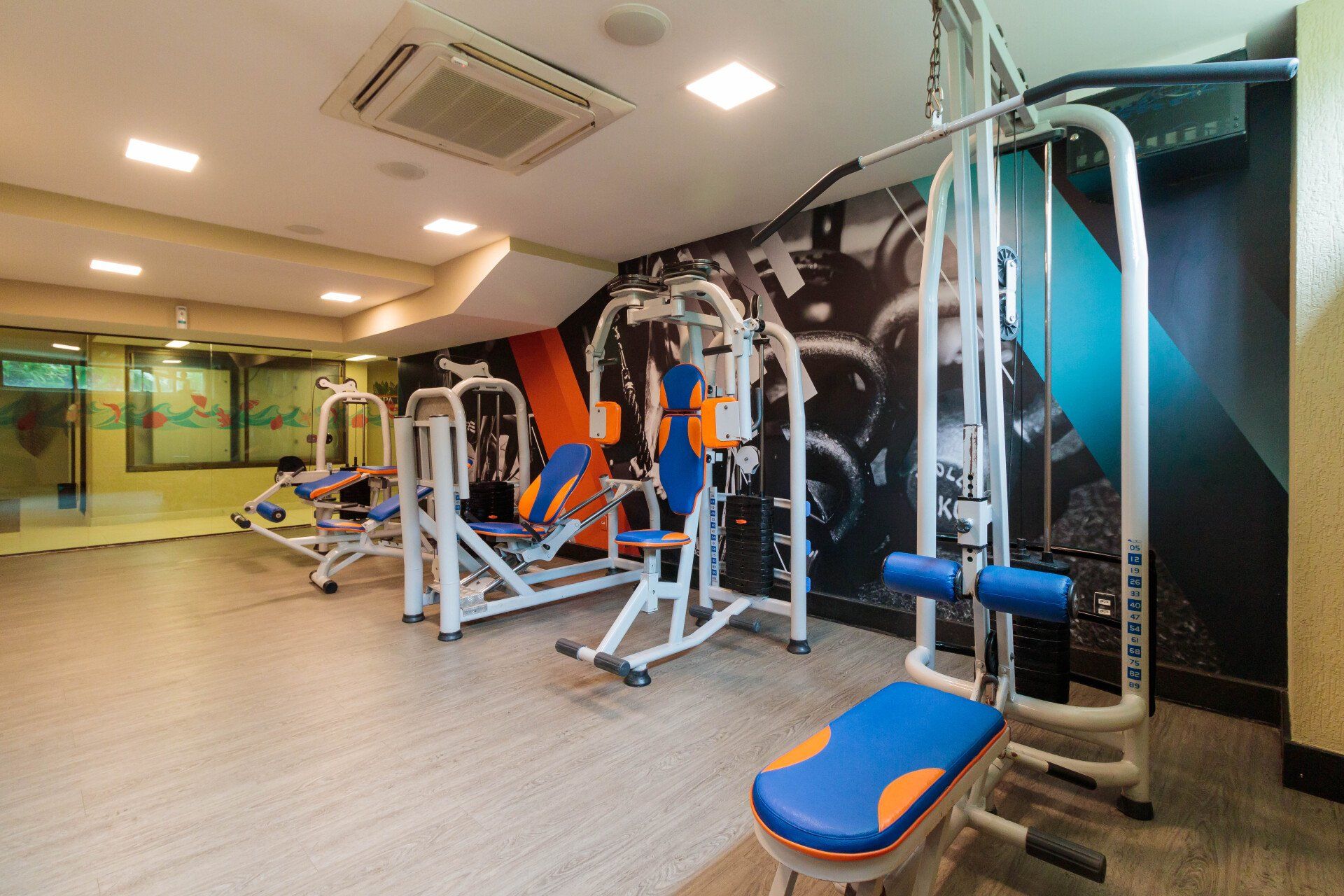 Uma academia com muitos equipamentos de exercícios e um banco.