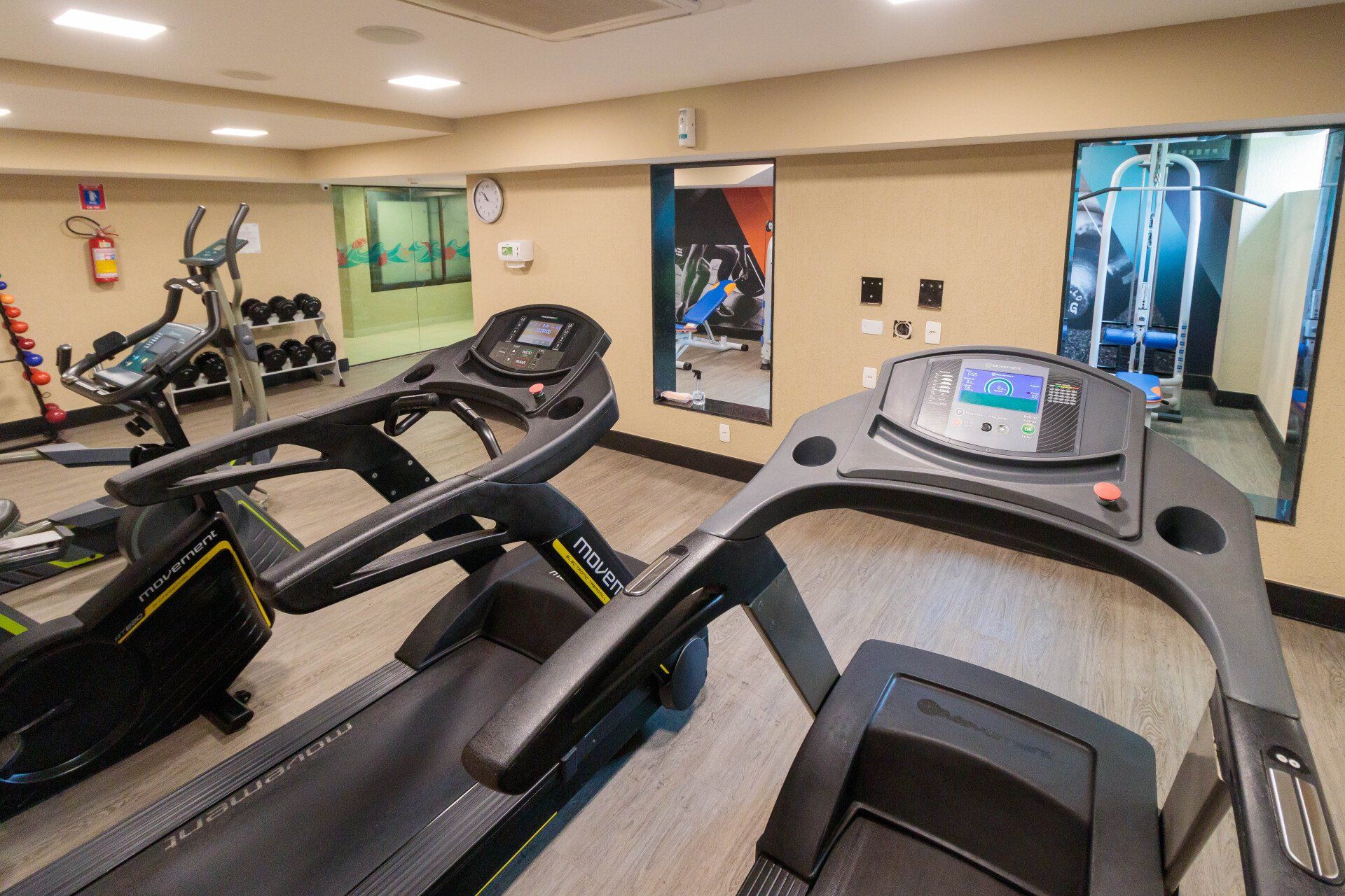 Uma academia com muitas esteiras e equipamentos de exercícios.