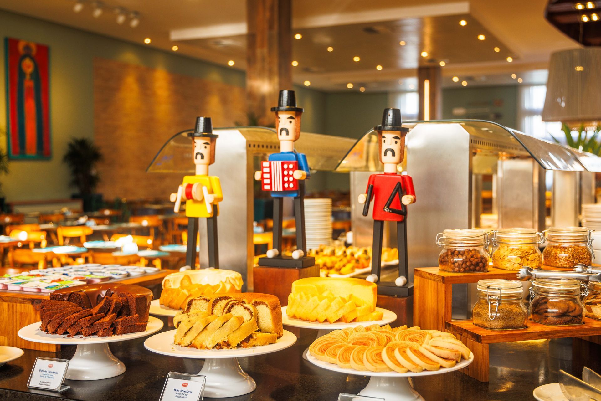 Uma mesa de bufê com uma variedade de sobremesas e estatuetas de madeira.