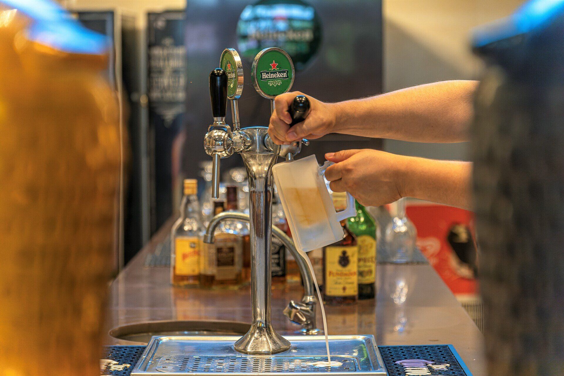 Uma pessoa está servindo cerveja em um copo em um bar.