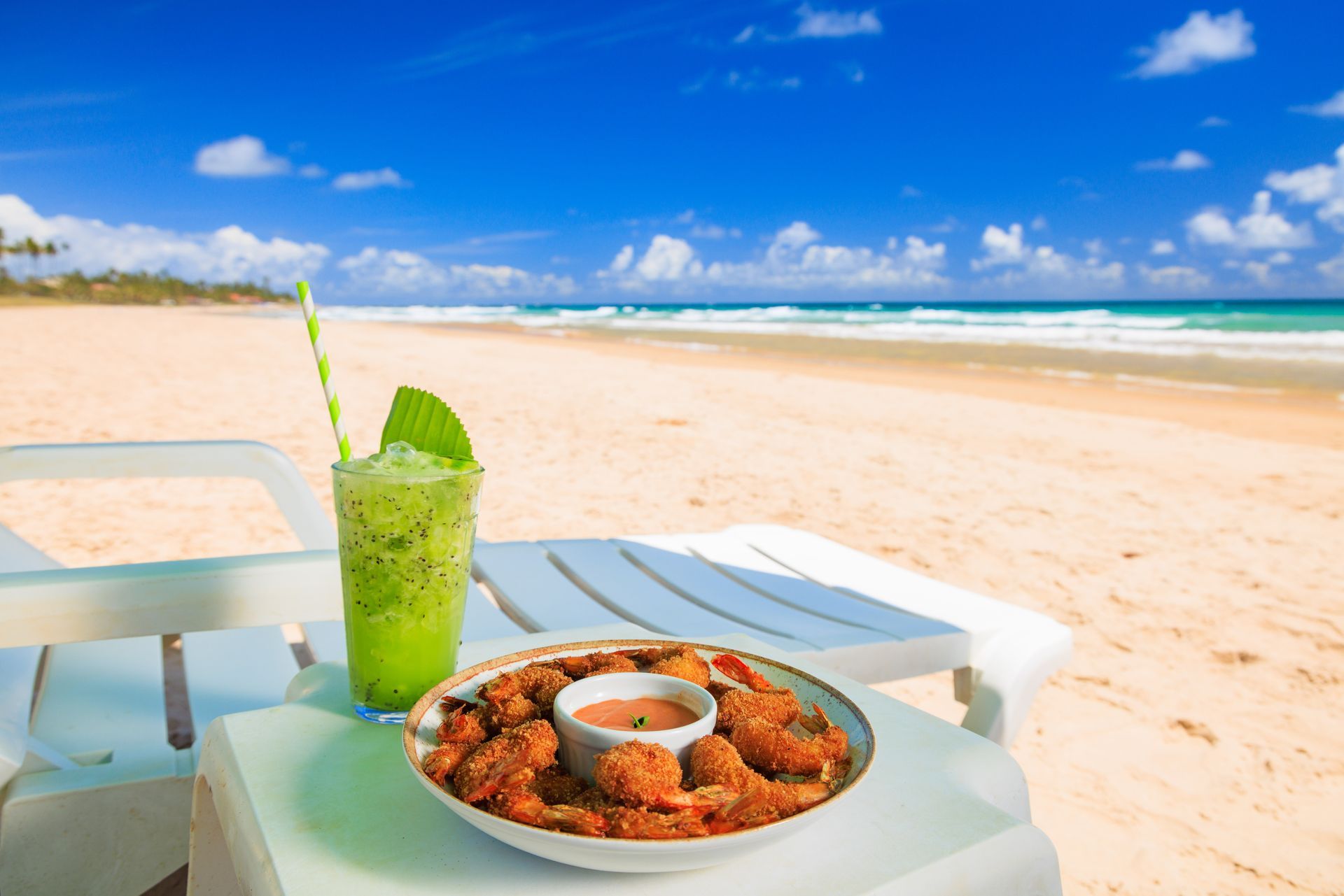 Um prato de comida e uma bebida em uma mesa na praia.