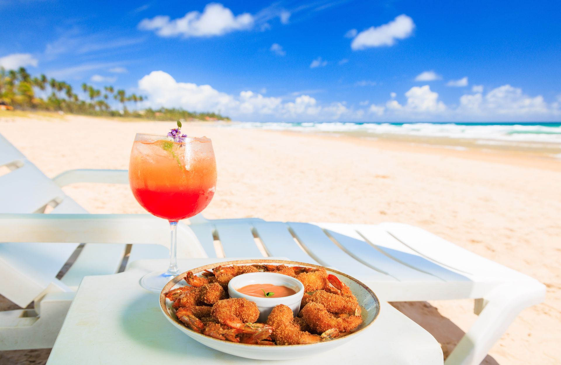 Um prato de comida e uma taça de vinho em uma mesa na praia.