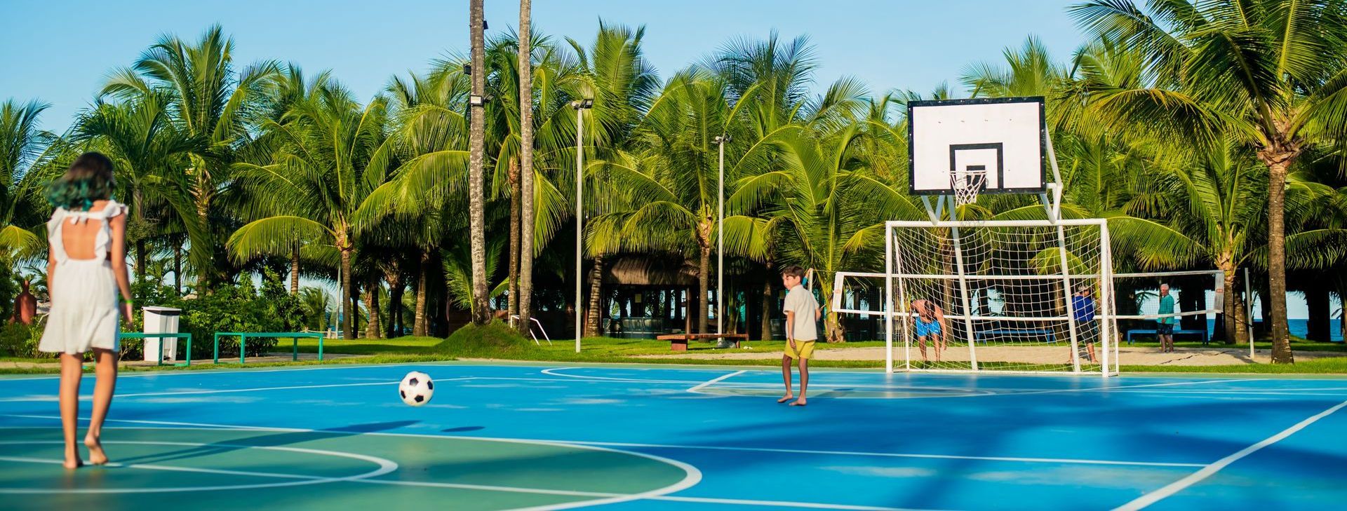 Uma mulher está jogando futebol em uma quadra de basquete.