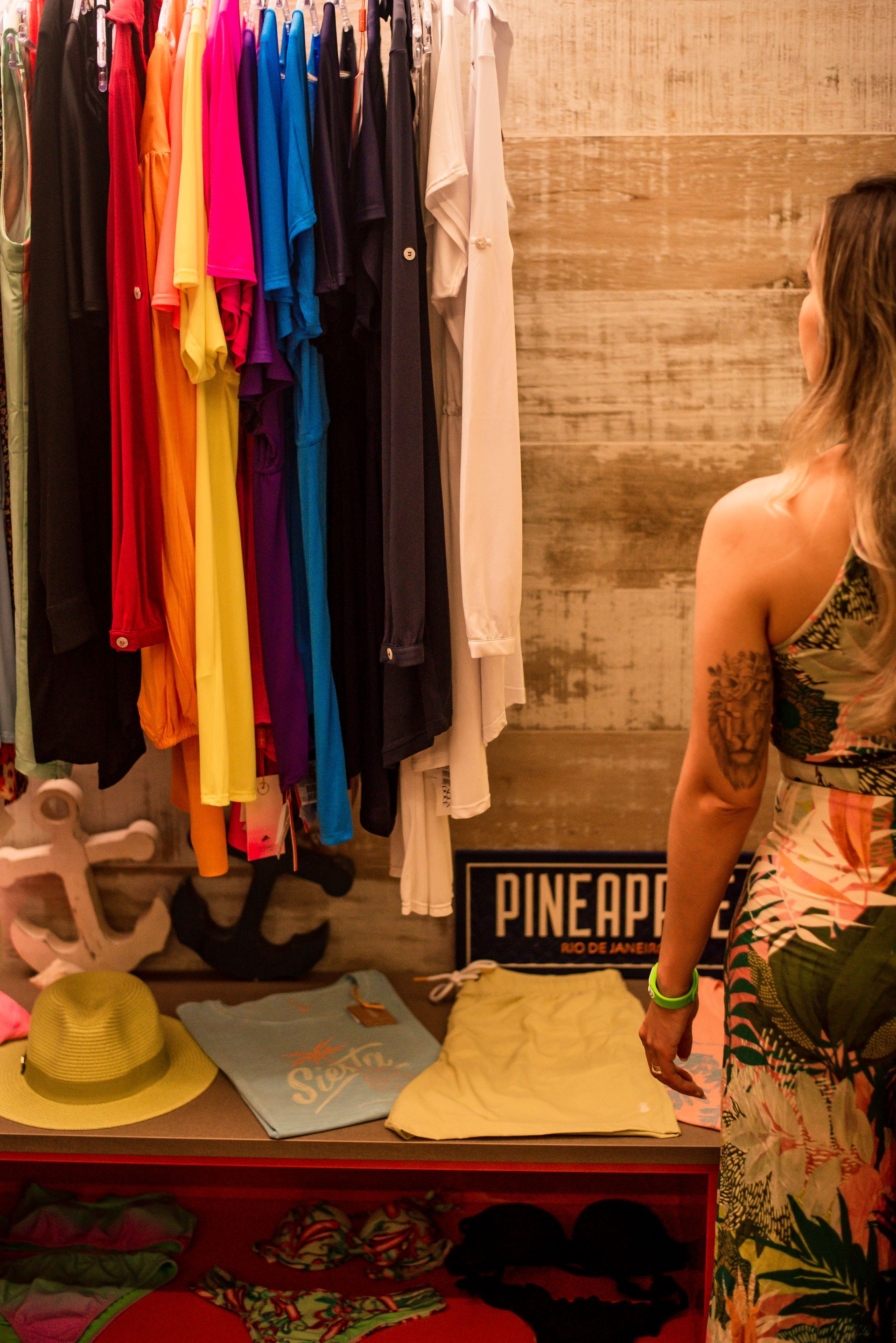 Uma mulher está parada em frente a uma vitrine de roupas em uma loja.