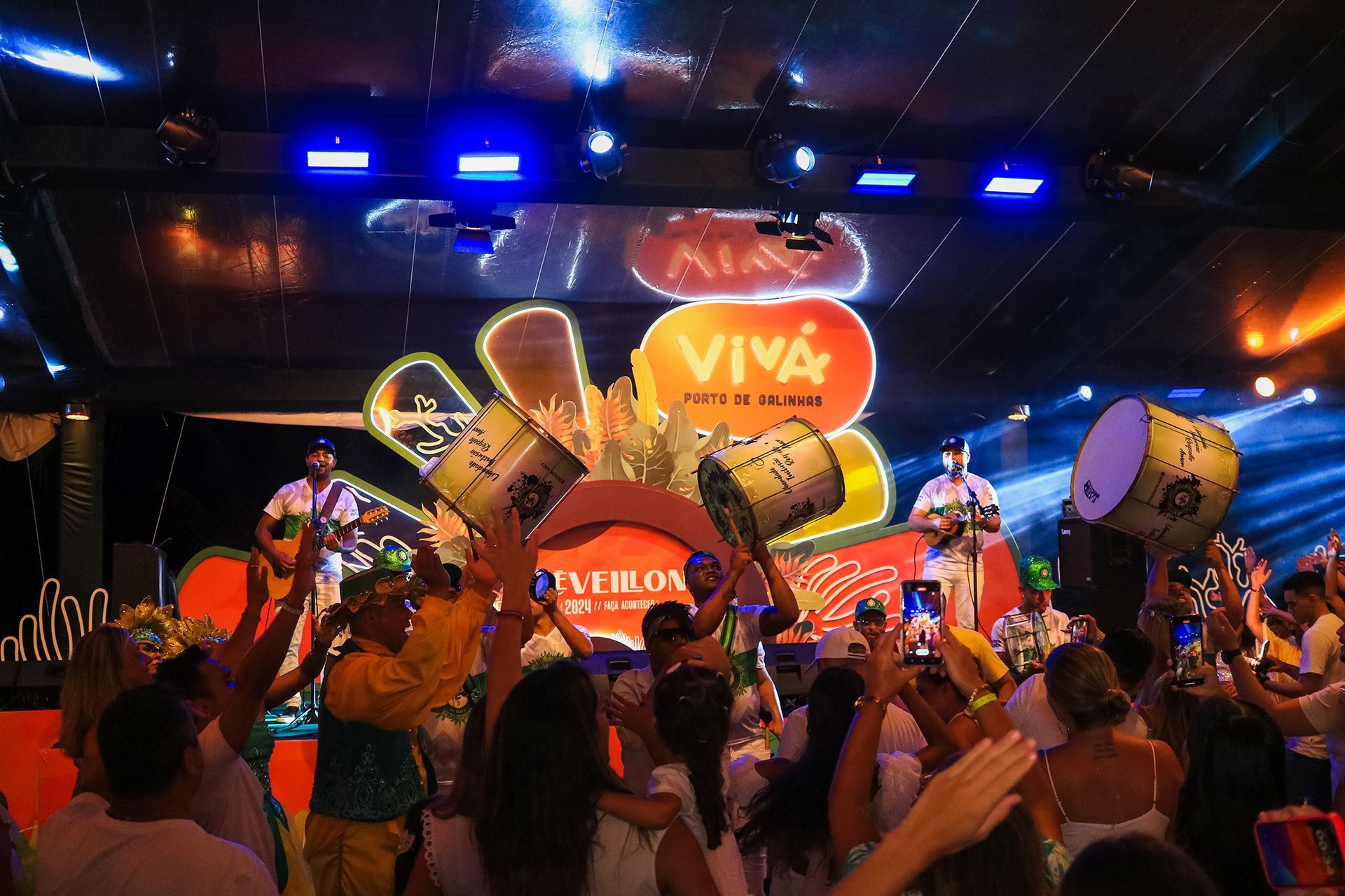 Uma multidão de pessoas está dançando em frente ao palco em um show.
