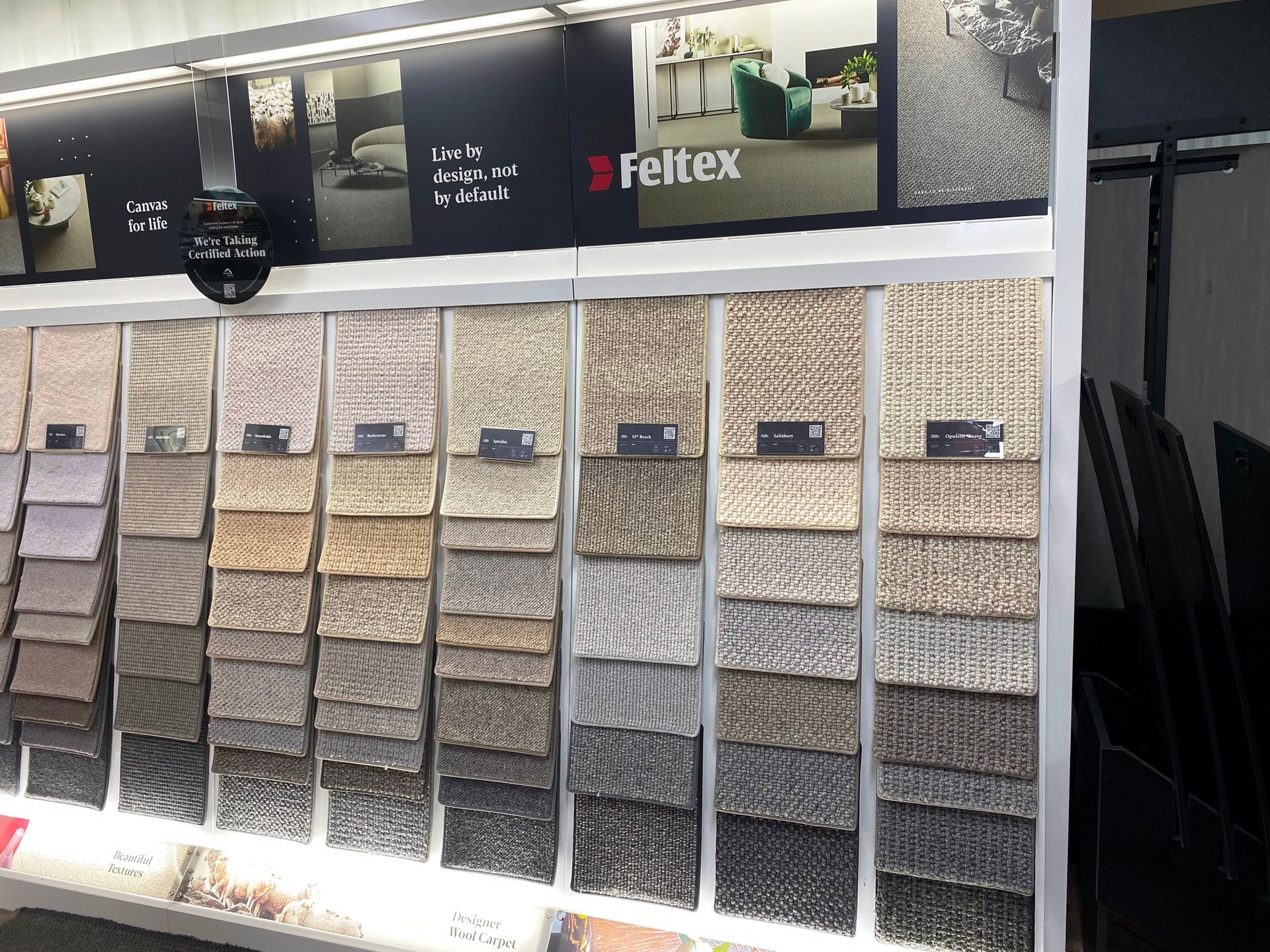 Carpet samples displayed on a rack. Various neutral colors and textures are shown.  Feltex logo present.