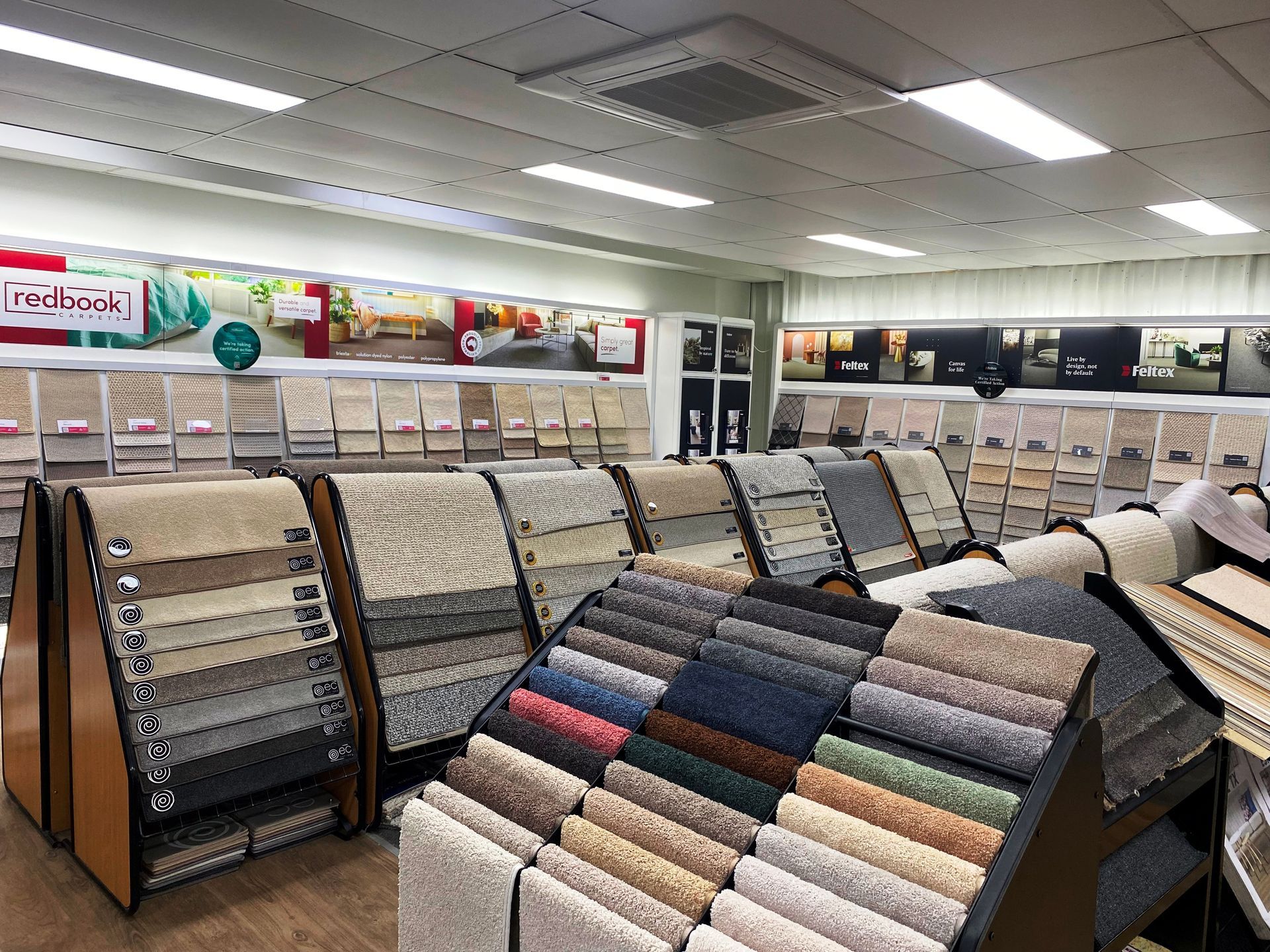 Carpet samples displayed in a brightly lit retail store; various colors and textures.