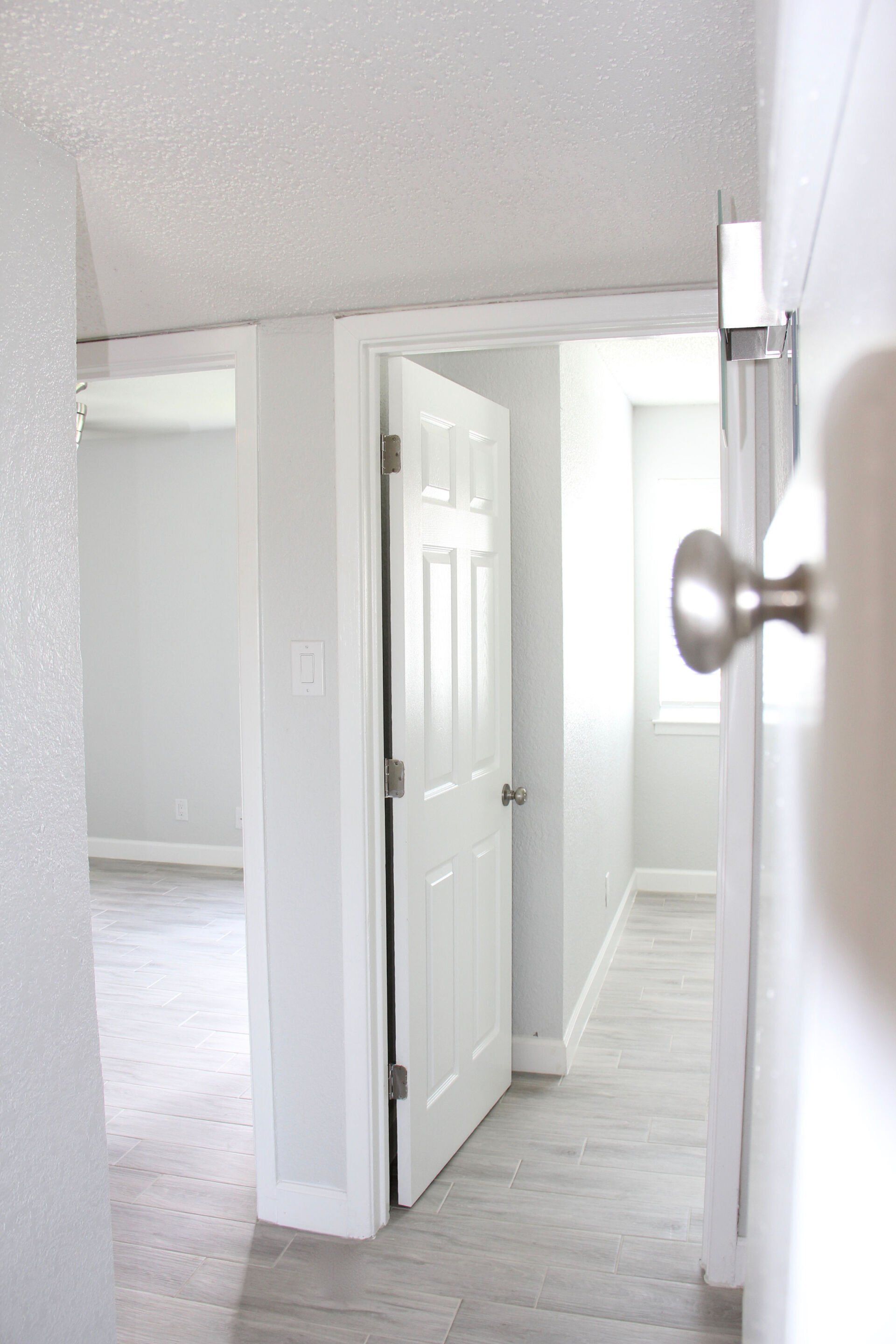 A hallway in a house with a door open and a door knob.