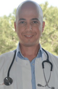 A bald man wearing a white coat and a stethoscope around his neck