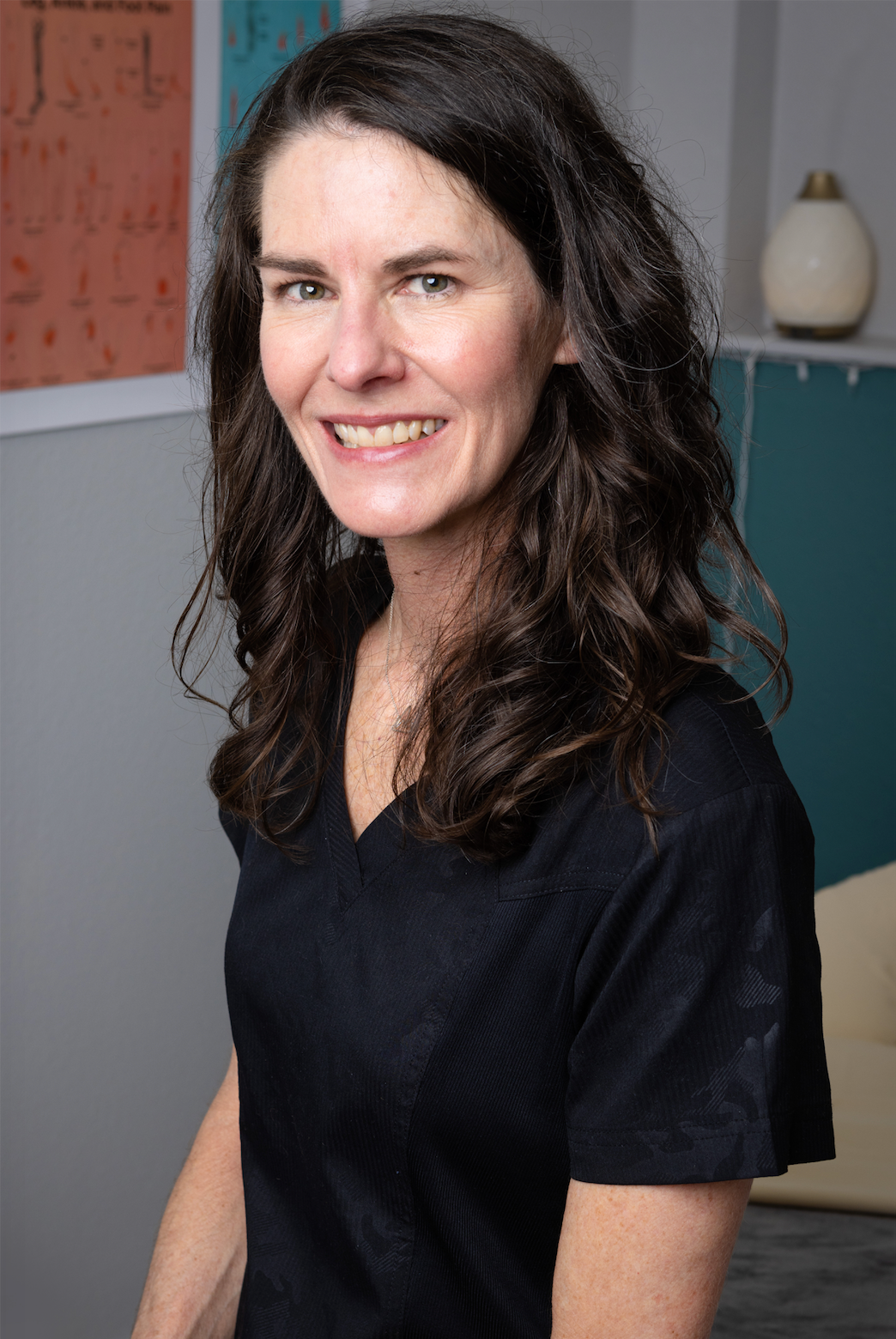 A woman wearing a blue turtleneck and earrings is smiling for the camera.