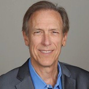 A man in a suit and blue shirt is smiling for the camera.