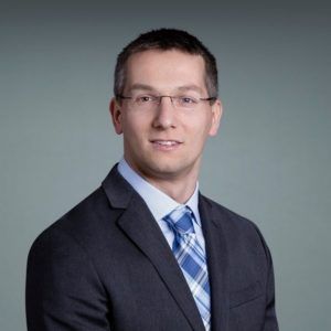 A man in a suit and tie is smiling for the camera