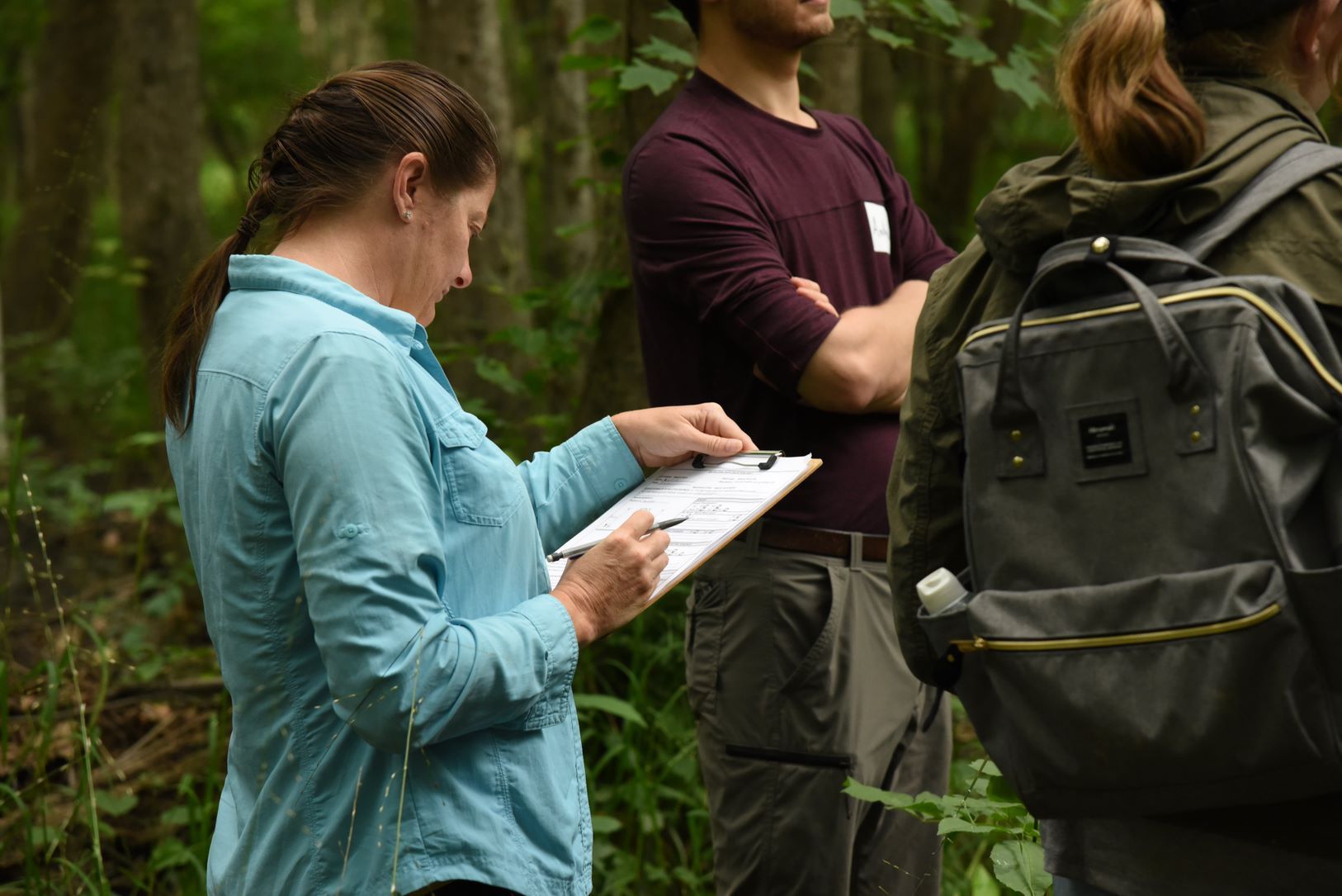 People completing a form on clipboard in the wetland.