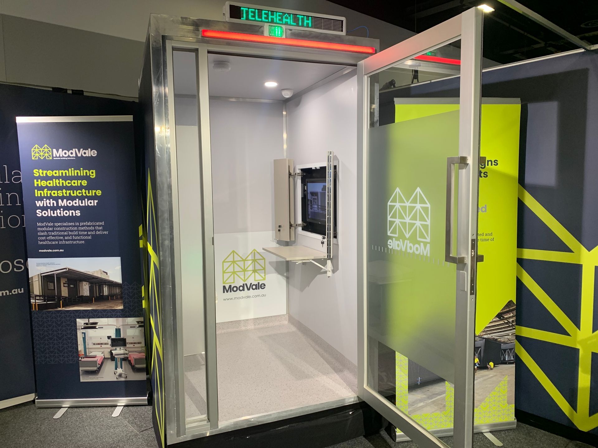 A small room with a glass door and a monitor on the wall.