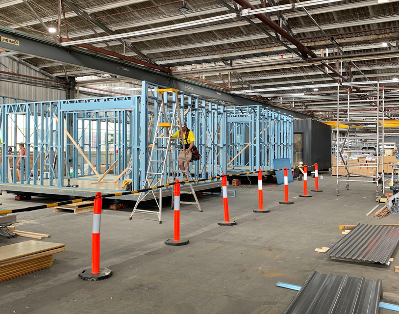 A man is standing on a ladder in a building under construction.
