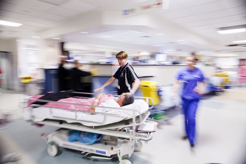 A woman is laying in a hospital bed on a stretcher.