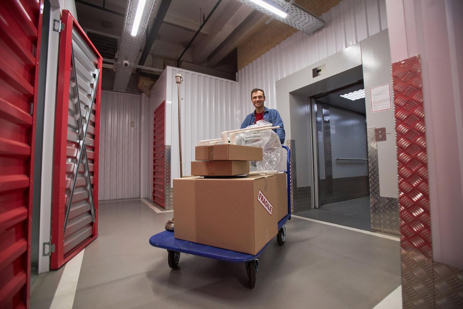 Delivery worker pushing a cart of boxes through a warehouse corridor