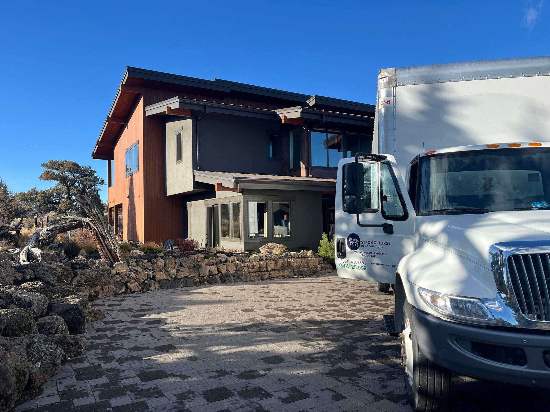 White truck parked beside a modern house with stone landscaping under a blue sky