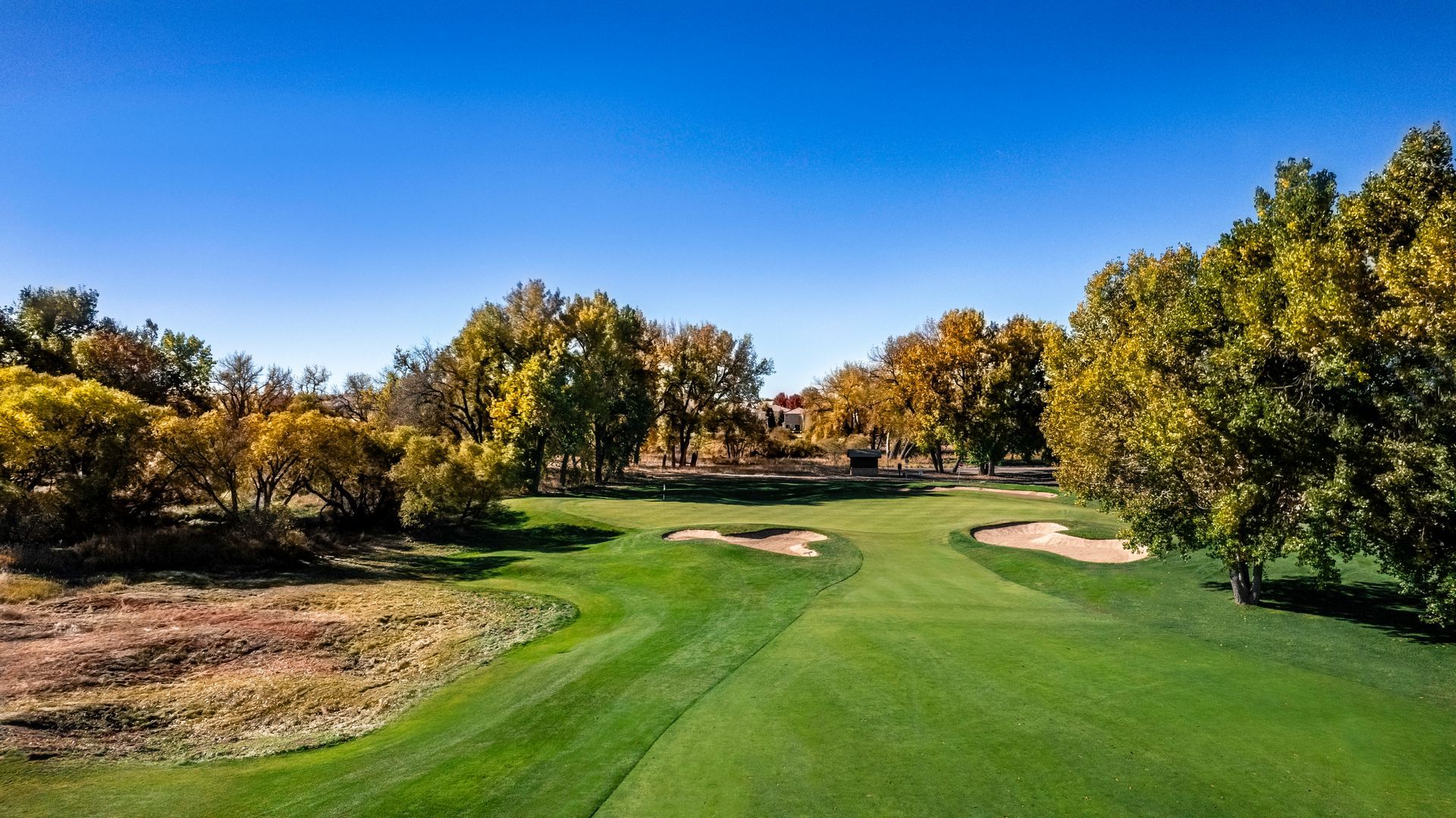 An aerial view of a golf course with houses in the background