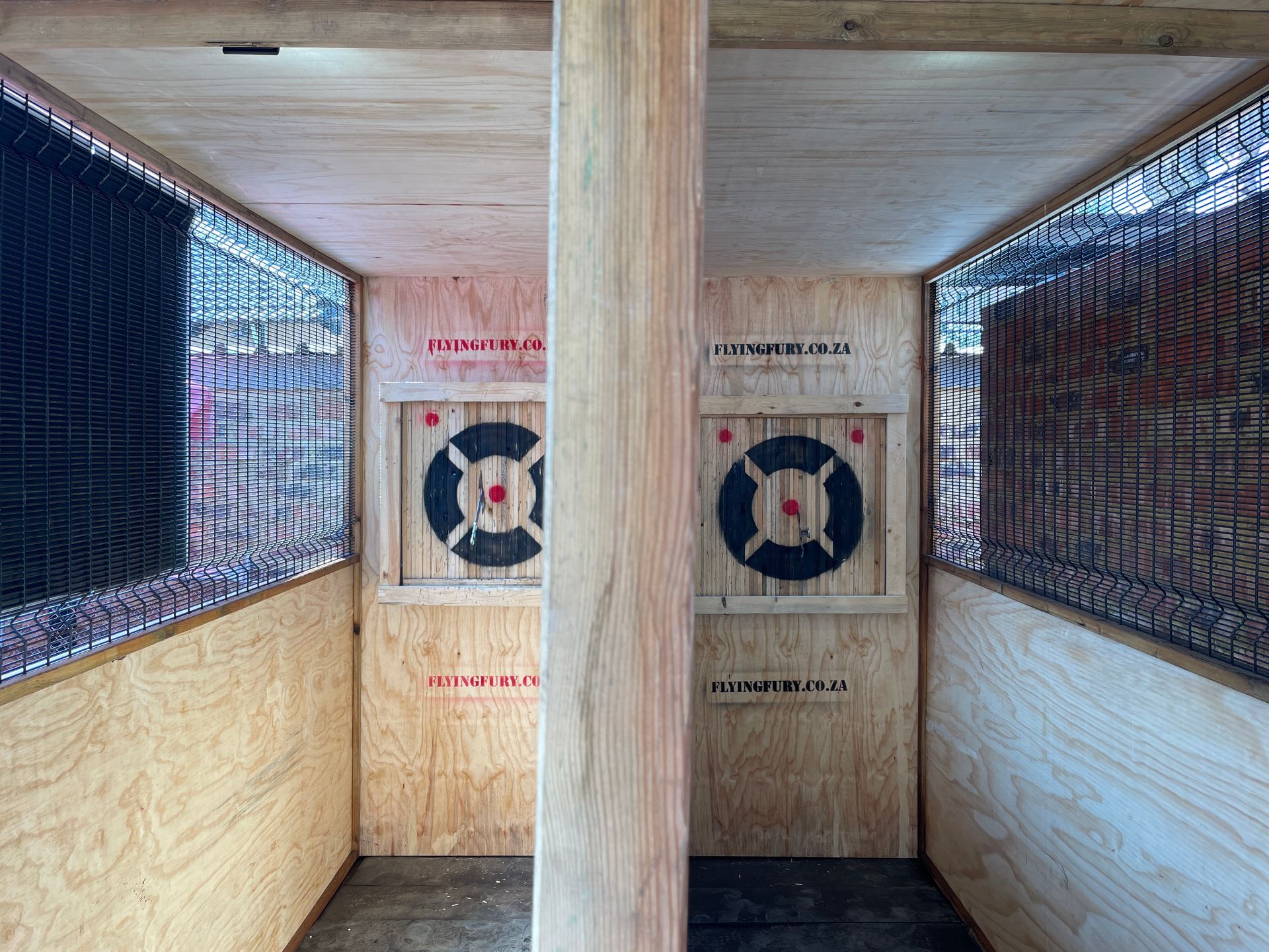 Two axe-throwing lanes with wooden targets, surrounded by wooden walls and safety netting.