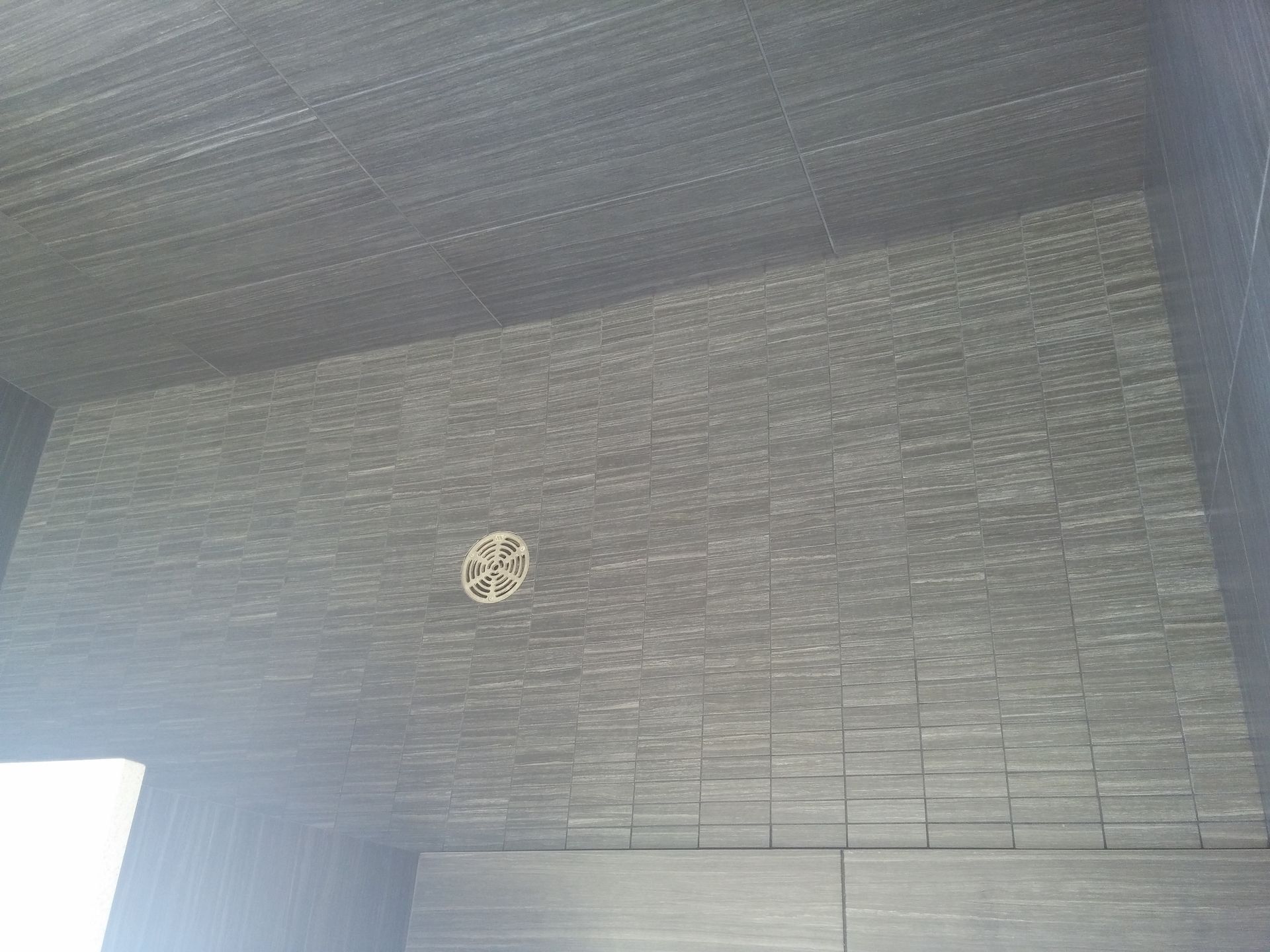 Dark gray tiled interior with a circular vent in the center of the wall.