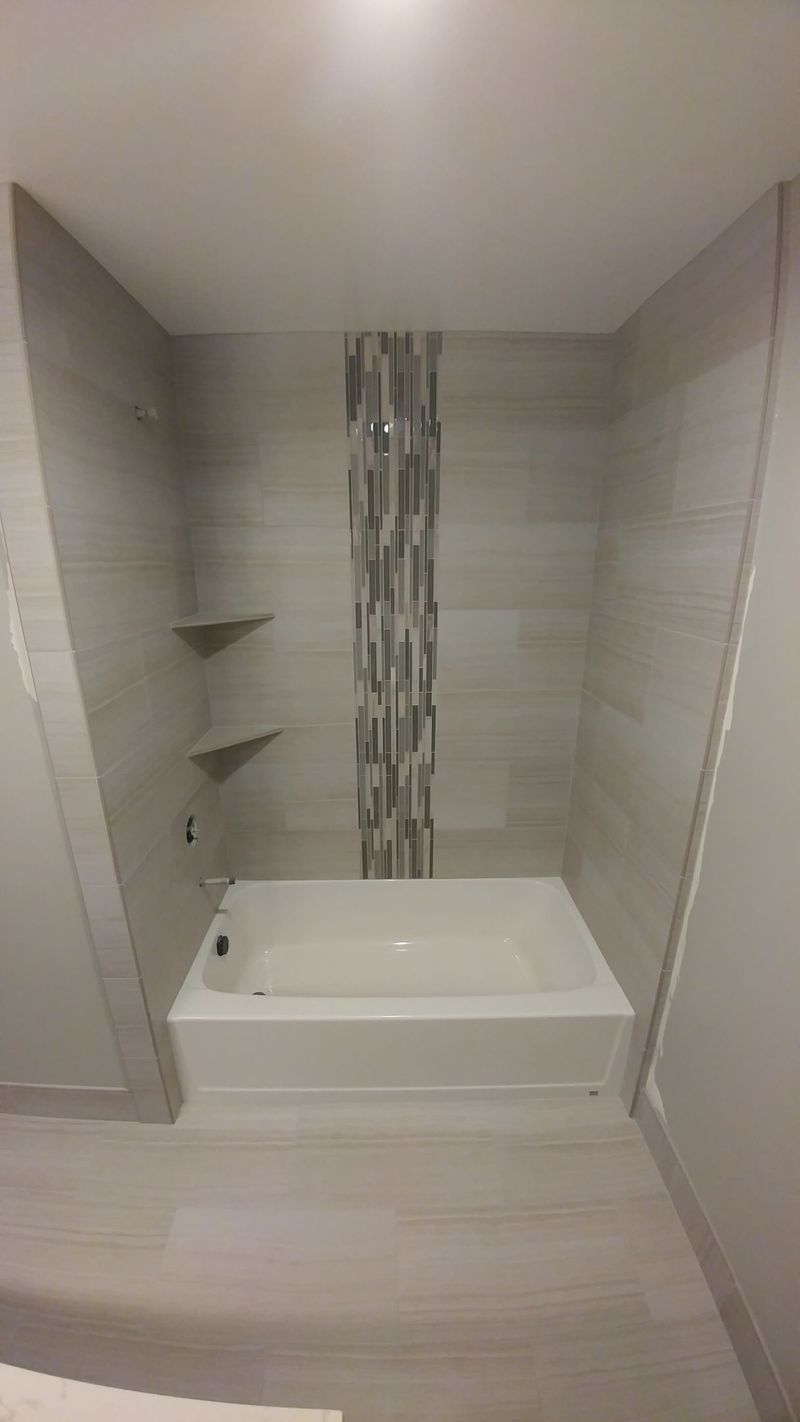 Bathroom with a rectangular tub, tiled walls, and shelves. Neutral colors, modern design.