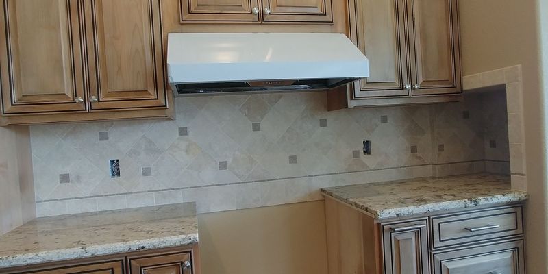 Kitchen with wooden cabinets, granite countertops, and tiled backsplash under a range hood.