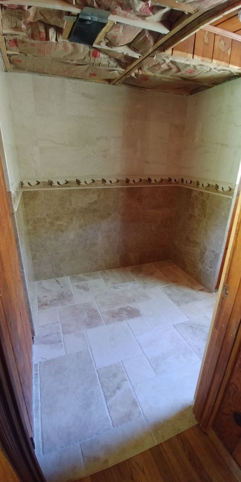 Interior view of a small room with stone flooring and unfinished walls, visible from a doorway.