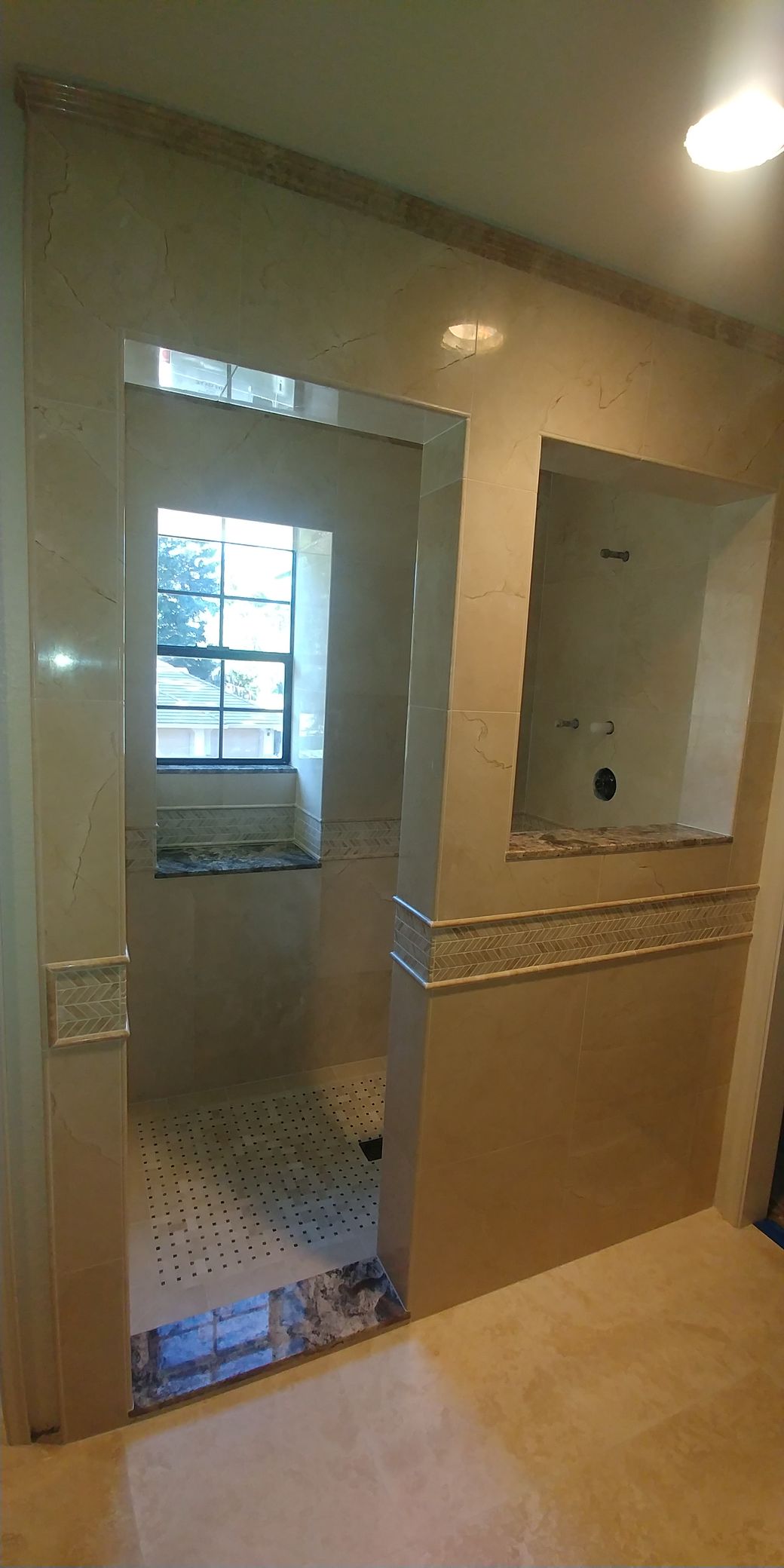 Bathroom with tiled walls and a shower entrance. Beige and stone accents.