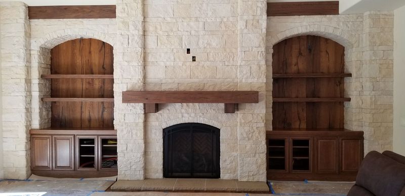 Stone fireplace with wooden shelves and cabinets built into the wall.